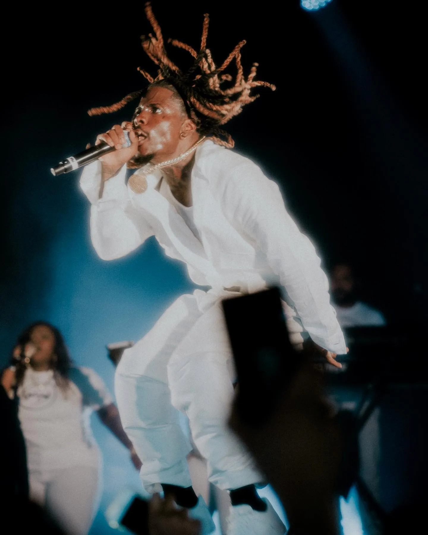 Matieu White en concert, tenue blanche sous les lumières bleues